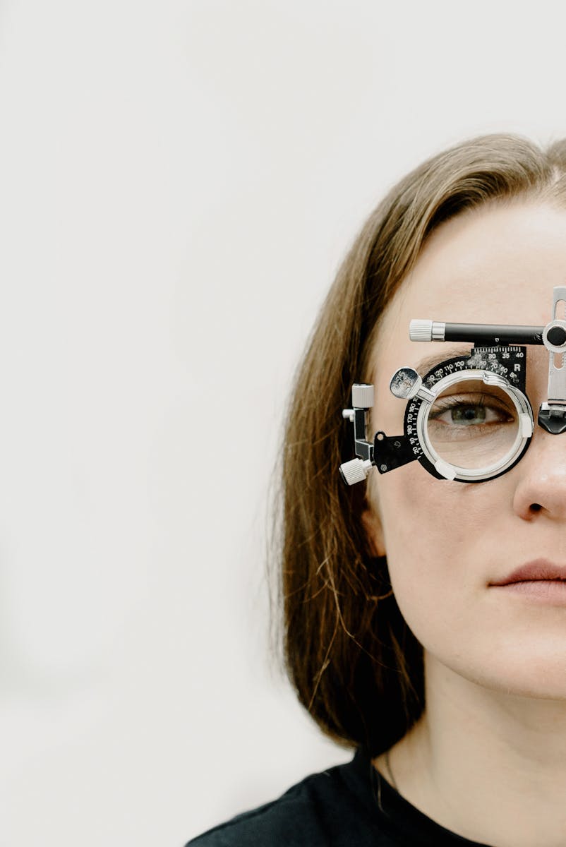 Close-up of woman wearing phoropter for vision test in a clinic setting.